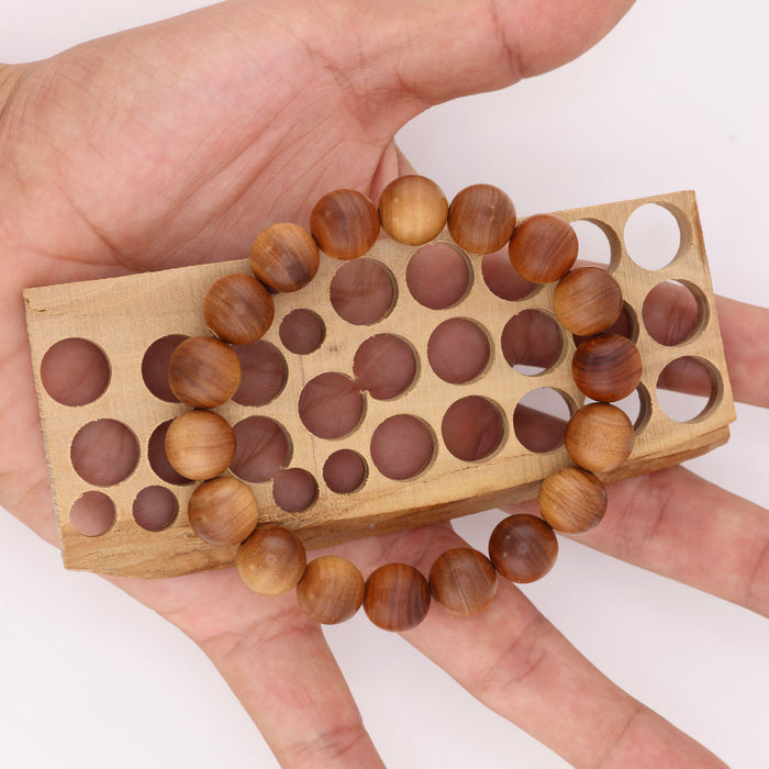 Buy natural sandalwood bracelet held over a wooden bead-sizing board