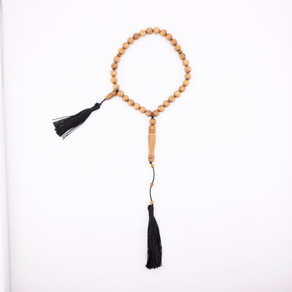 Sandalwood prayer strand for sale with 33 beads, black tassels, and a carved wooden centerpiece