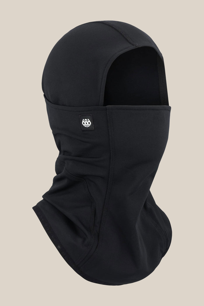 The 686 Alpha Hinged Balaclava in black features smooth fabric, covers the head, neck, and lower face with an eye opening, and displays a small 686 logo patch on the side. Set against a solid light beige background.