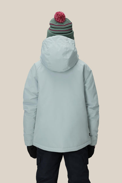 A person wearing the 686 Girls' Hydra™ Insulated Jacket by 686, paired with a green beanie with a red pom-pom, black gloves, and dark pants, stands with their back to the camera against a beige background.