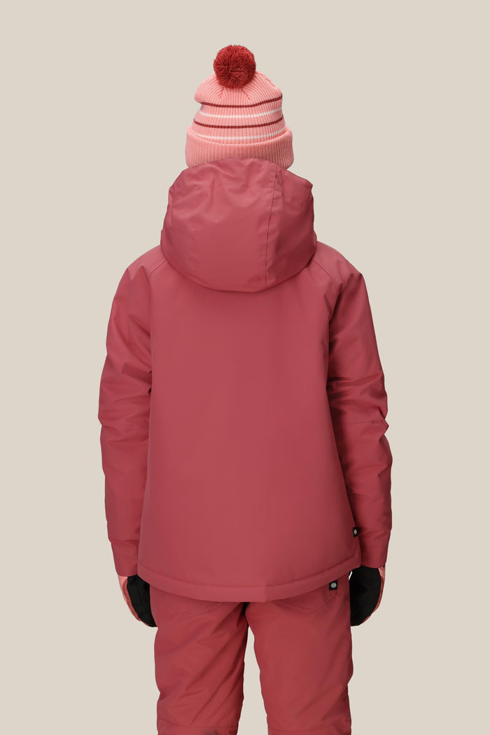 Facing away, a person wears the 686 Girls' Hydra™ Insulated Jacket by 686 in pink with matching pants, black gloves, and a pink beanie topped with a red pom-pom, set against a plain beige background.