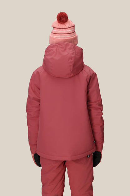 Facing away, a person wears the 686 Girls' Hydra™ Insulated Jacket by 686 in pink with matching pants, black gloves, and a pink beanie topped with a red pom-pom, set against a plain beige background.