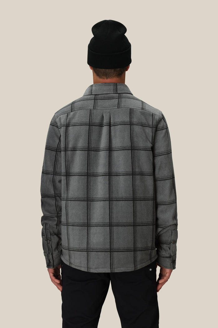 A person is shown from the back wearing the 686 Mens Sierra Fleece Flannel in black, standing against a plain light beige background‚Äîa perfect layering piece for spring riding.