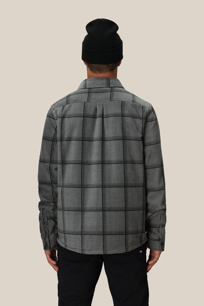 A person is shown from the back wearing the 686 Mens Sierra Fleece Flannel in black, standing against a plain light beige background‚Äîa perfect layering piece for spring riding.