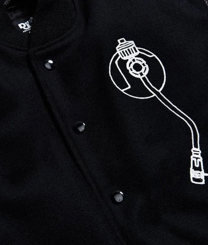 Zoom  catalog layout of the Leveljacket Def Jam Recordings black varsity jacket, displaying a premium black wool body with black leather sleeves, custom white embroidered turntable needle art on the front chest, and a bold white Def Jam Recordings typography patch layout across the back.