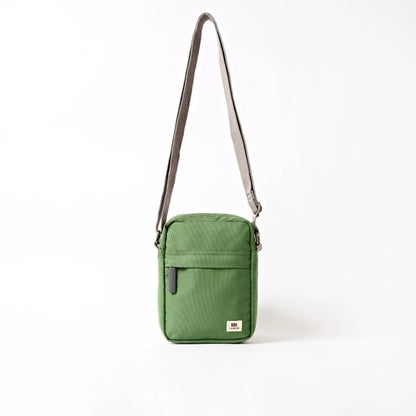 Green canvas crossbody bag with zip top, front pocket, and adjustable shoulder strap