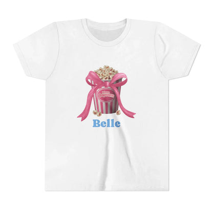 White t-shirt with popcorn bucket graphic, pink ribbon, and blue text 'Belle'