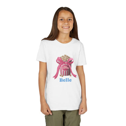 Smiling girl wearing white t-shirt with pink popcorn bucket and bow design and name Belle