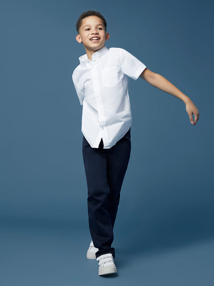DL1961 boys' Brady Slim jeans in navy 'Dark Sapphire' on child model mid-stride, three-quarter view.
