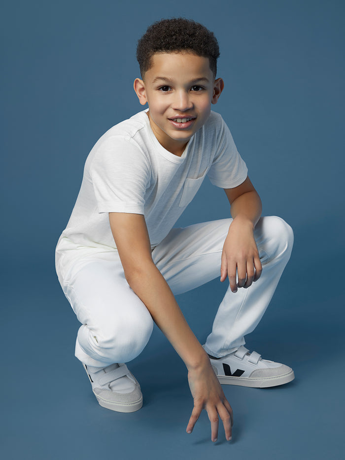 DL1961 boys' Brady Slim jeans in white 'Medallion' on child model crouching with white tee, front view.