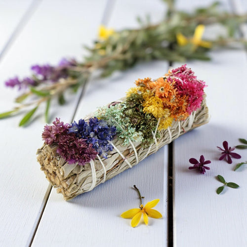 Colorful dried flower bundle on a wooden surface with additional flowers in the background.