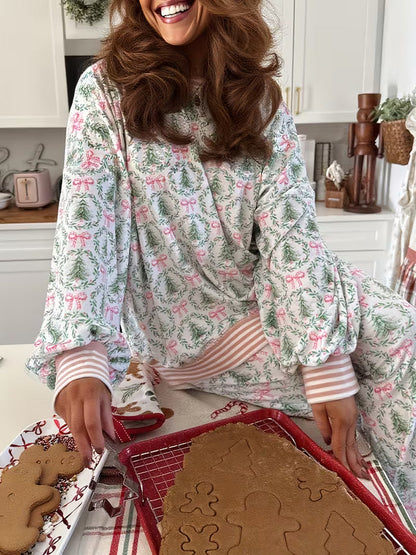 Woman in a floral pajama set cutting out gingerbread cookies on a baking sheet.