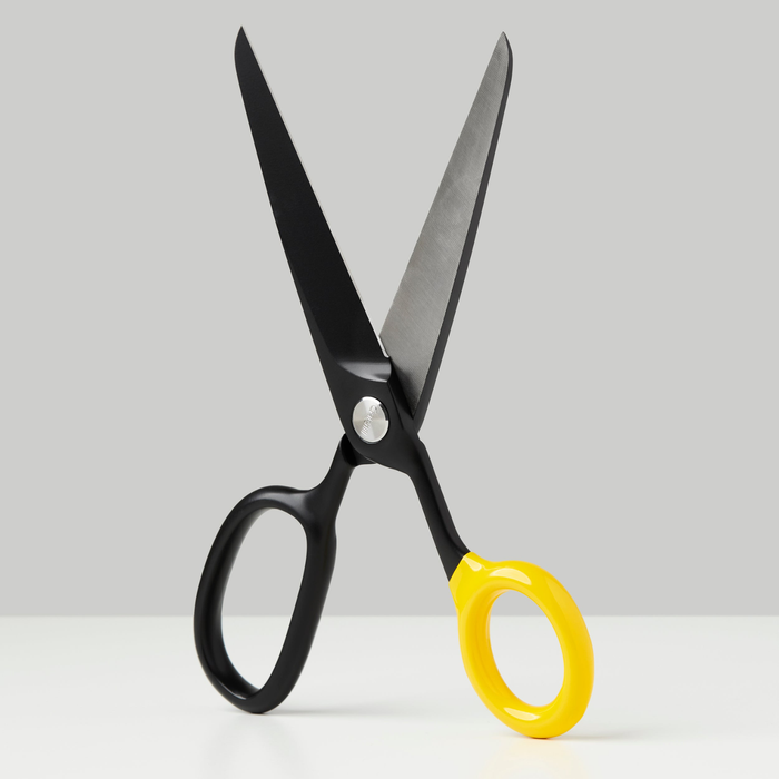 Black scissors with yellow finger rings, open blades and pivot screw