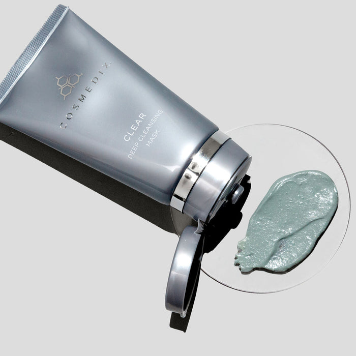 Tilted CosMedix Clear Deep Cleansing Mask tube with open cap and a dollop of mask on a white plate