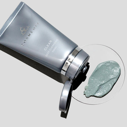 Tilted CosMedix Clear Deep Cleansing Mask tube with open cap and a dollop of mask on a white plate