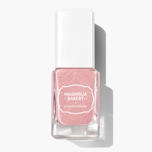 A clear glass bottle of pastel pink glitter nail polish labeled “LONDONTOWN Confetti Cake” with a white rectangular cap, photographed on a white background.