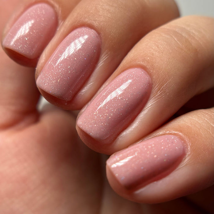 A close-up of a hand with neatly manicured nails painted in LONDONTOWN’s Confetti Cake—a glossy, sweet pink polish with fine shimmer.