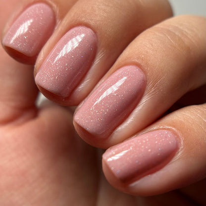 A close-up of a hand with neatly manicured nails painted in LONDONTOWN’s Confetti Cake—a glossy, sweet pink polish with fine shimmer.