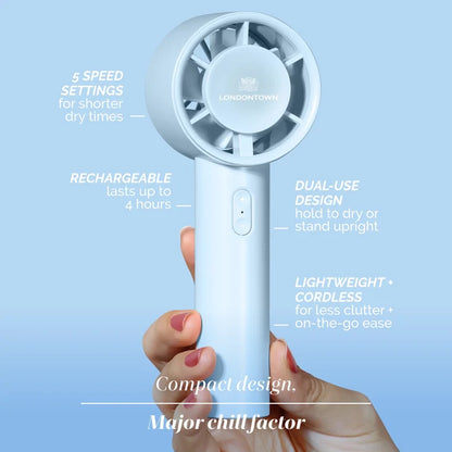 A hand holds the LONDONTOWN Cool Set Nail Fan - Ocean, a small, light blue handheld fan with labeled features such as 5 speed settings, a rechargeable battery, and a dual-use design for faster dry times.