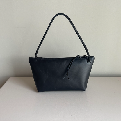 Dark cord pouch with black braided handle and small drawstring tie at top.