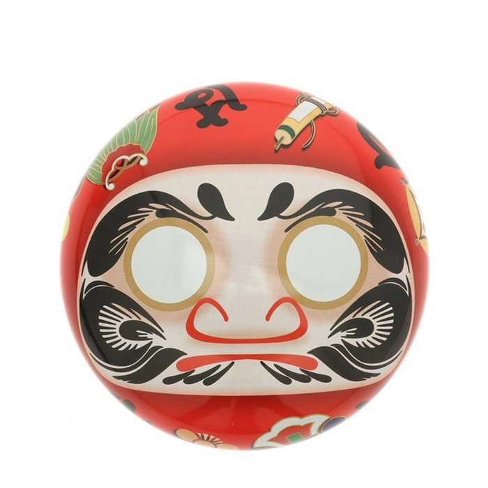 Red Daruma doll tea canister with black and white face design on a white background
