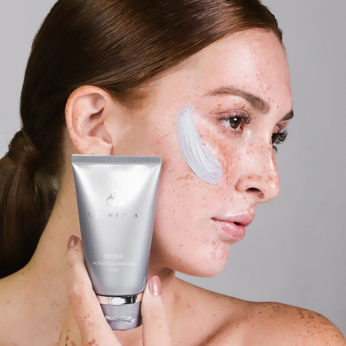Side profile of a woman with Detox Activated Charcoal Mask applied to her face and the tube visible near her cheek