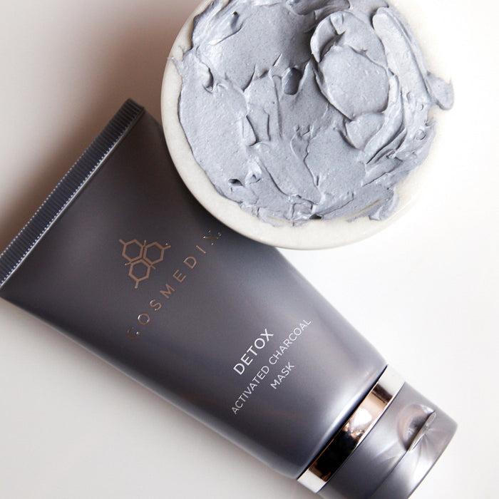 Close up of charcoal chunks and a Detox Activated Charcoal Mask tube on a plate