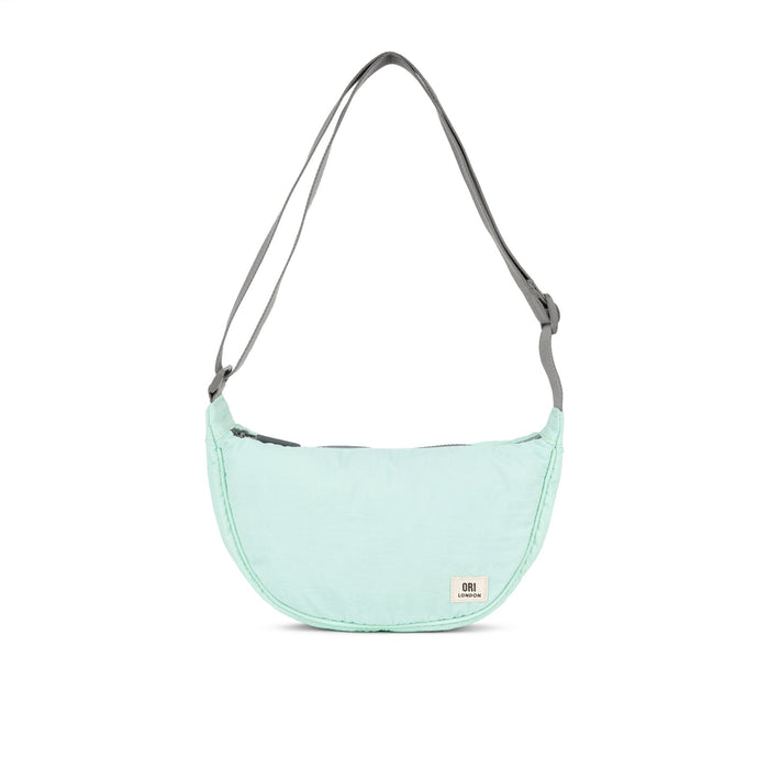Mint half-moon crossbody bag with gray webbing strap and curved zip top.
