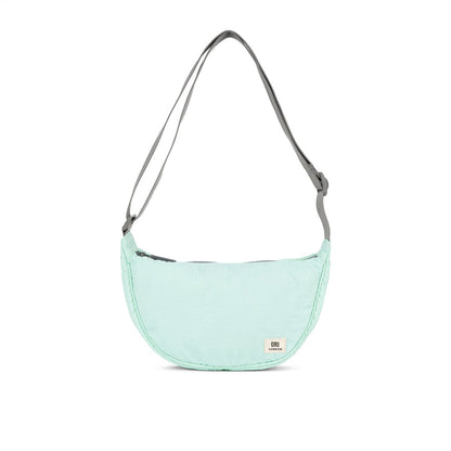 Mint half-moon crossbody bag with gray webbing strap and curved zip top.