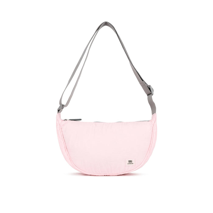 Seashell pink half-moon crossbody bag with gray webbing straps and zip top.