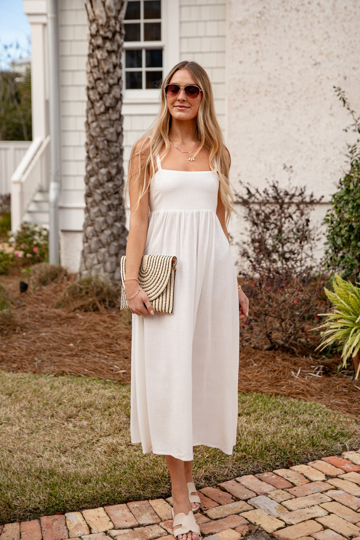 Woman in a white dress standing outdoors near a building