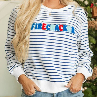Woman wearing white and blue striped sweatshirt with colorful 'FIRECRACKER' text, casual holiday style