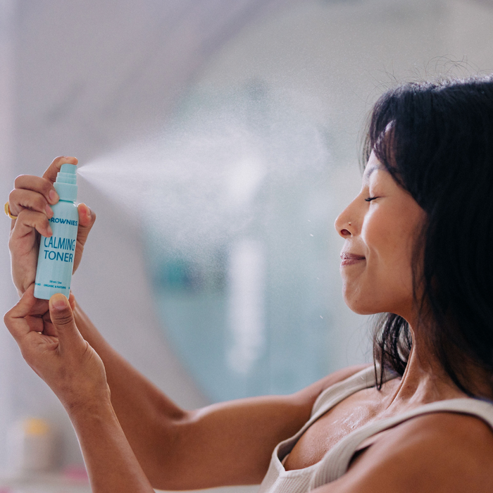 Frownies calming toner being sprayed on a woman's face