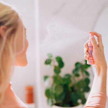 Frownies rose water hydrator spray being sprayed onto a woman's face