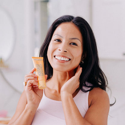 Frownies moisturizer for face and neck being held by a woman with black hair