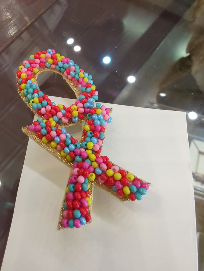 Colorful beaded pins by Camel Threads featuring vibrant, handcrafted designs perfect for accessories and clothing embellishments.