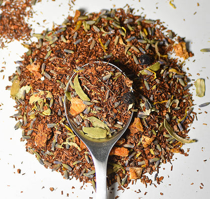 Lake Missoula Tea Company's Gin & Cream herbal tea in a teacup with a tea bag and fresh herbs on a wooden table.