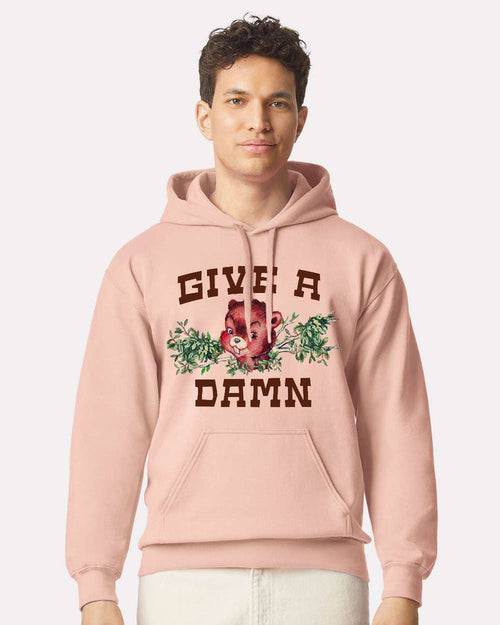 Pink "Give a Damn" hoodie by The Coin Laundry, front view showing the hoodie with bold text design and soft fabric texture.
