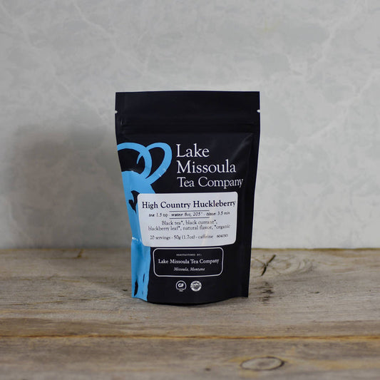 Lake Missoula Tea Company High Country Huckleberry tea in a cup with fresh huckleberries and tea leaves, ready to enjoy.