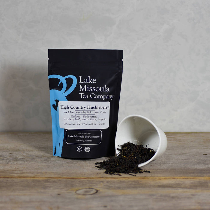 Lake Missoula Tea Company High Country Huckleberry tea in a teacup with fresh huckleberries and tea leaves.