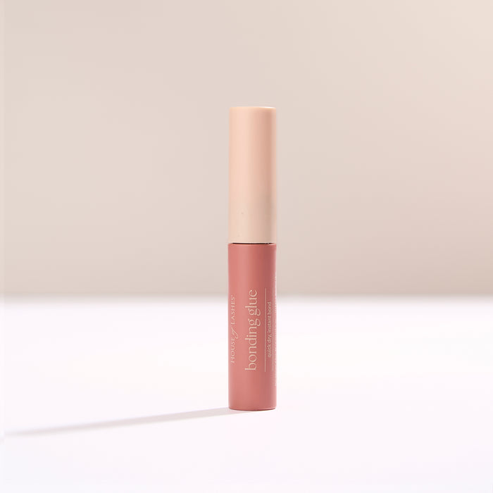 HOL bonding glue tube standing upright with pale pink cap against a soft beige backdrop