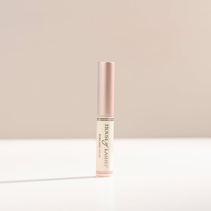 Clear lash glue on a beige background.