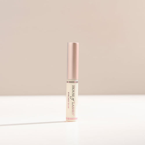 Clear lash glue on a beige background.
