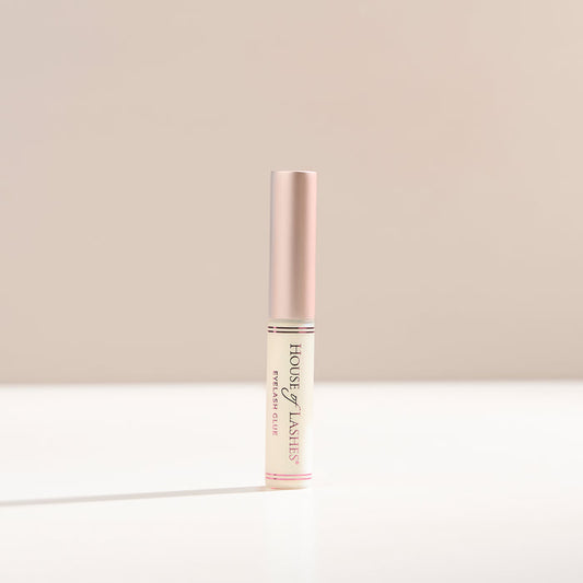 Clear lash glue on a beige background.