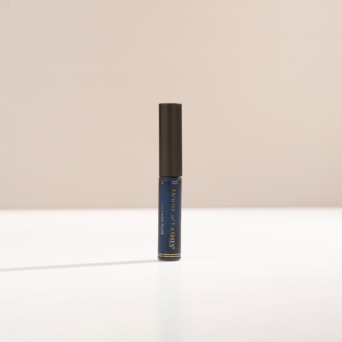 HOL® DARK Lash Glue on a beige background.