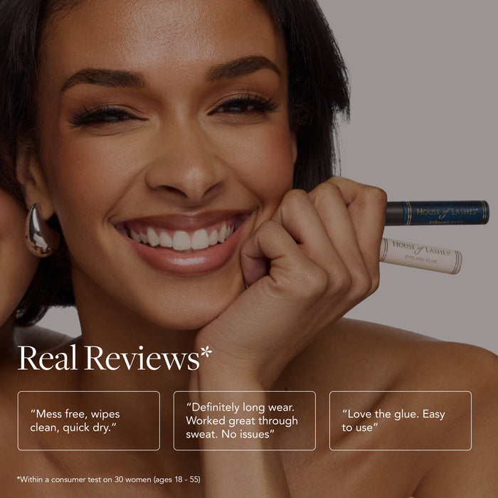 Smiling woman holding HOL Dark Lash Glue tube near her lashes
