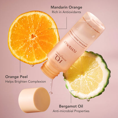 Mandarin orange half and bergamot oil highlights beside a tilted HOL Lash Glue Eye Makeup Remover bottle.