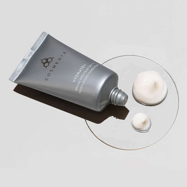 Hydrate+ SPF Moisturizing Sunscreen tube with cream swatches on a pale surface