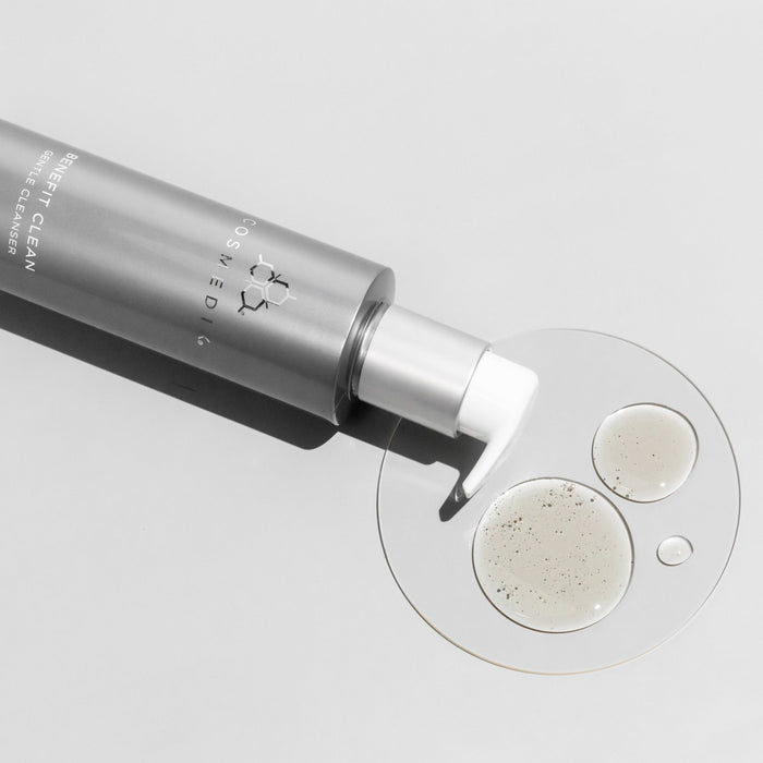 Cosmedix bottle dispensing cleanser onto a clear circular pad with two dots of cream.