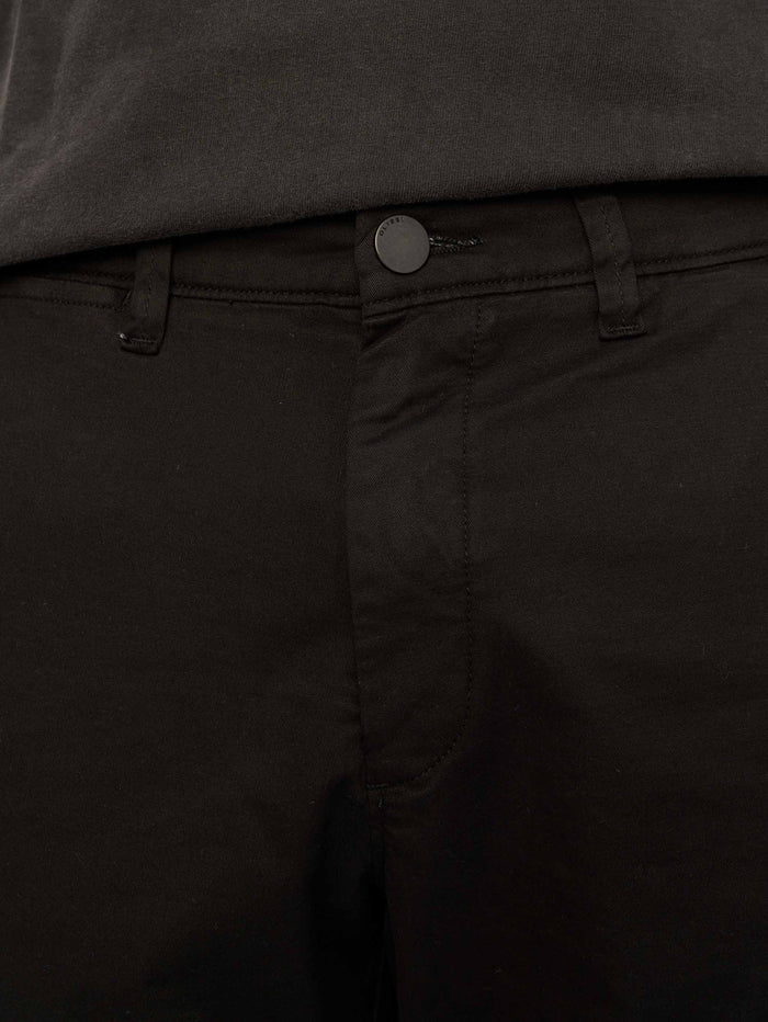 DL1961 men's Jake chino short in black, close-up of front button and fly.